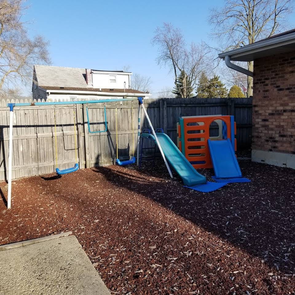 Backyard playground with swings, slide, and playhouse
