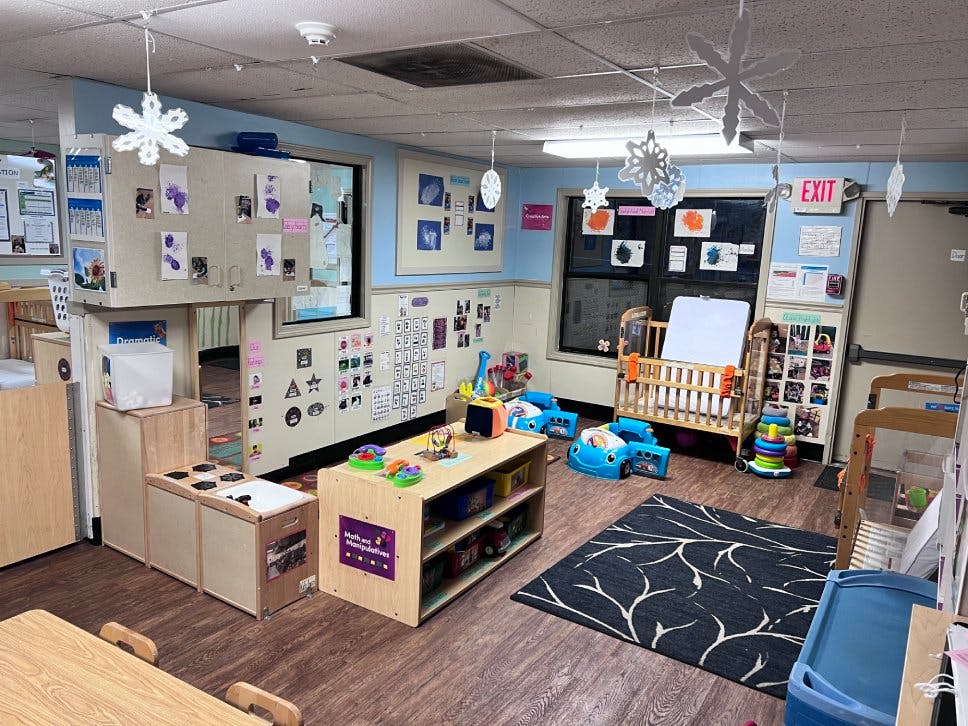 Classroom with play furniture, cribs, and child artwork on walls