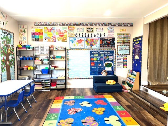 Classroom with colorful rug, tables, chairs, shelves, and wall decorations