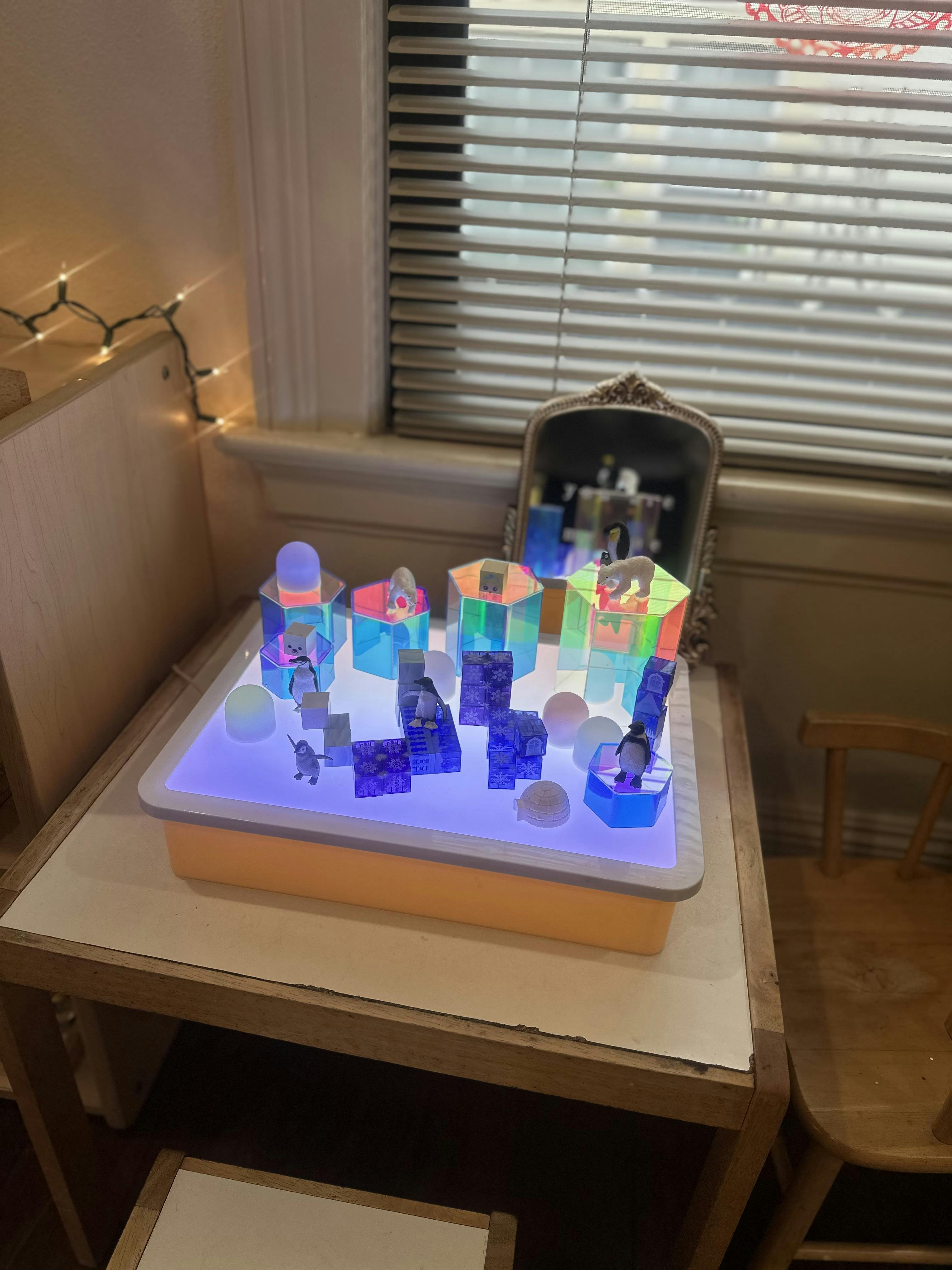 Plastic toy animals and geometric blocks on a glowing light table