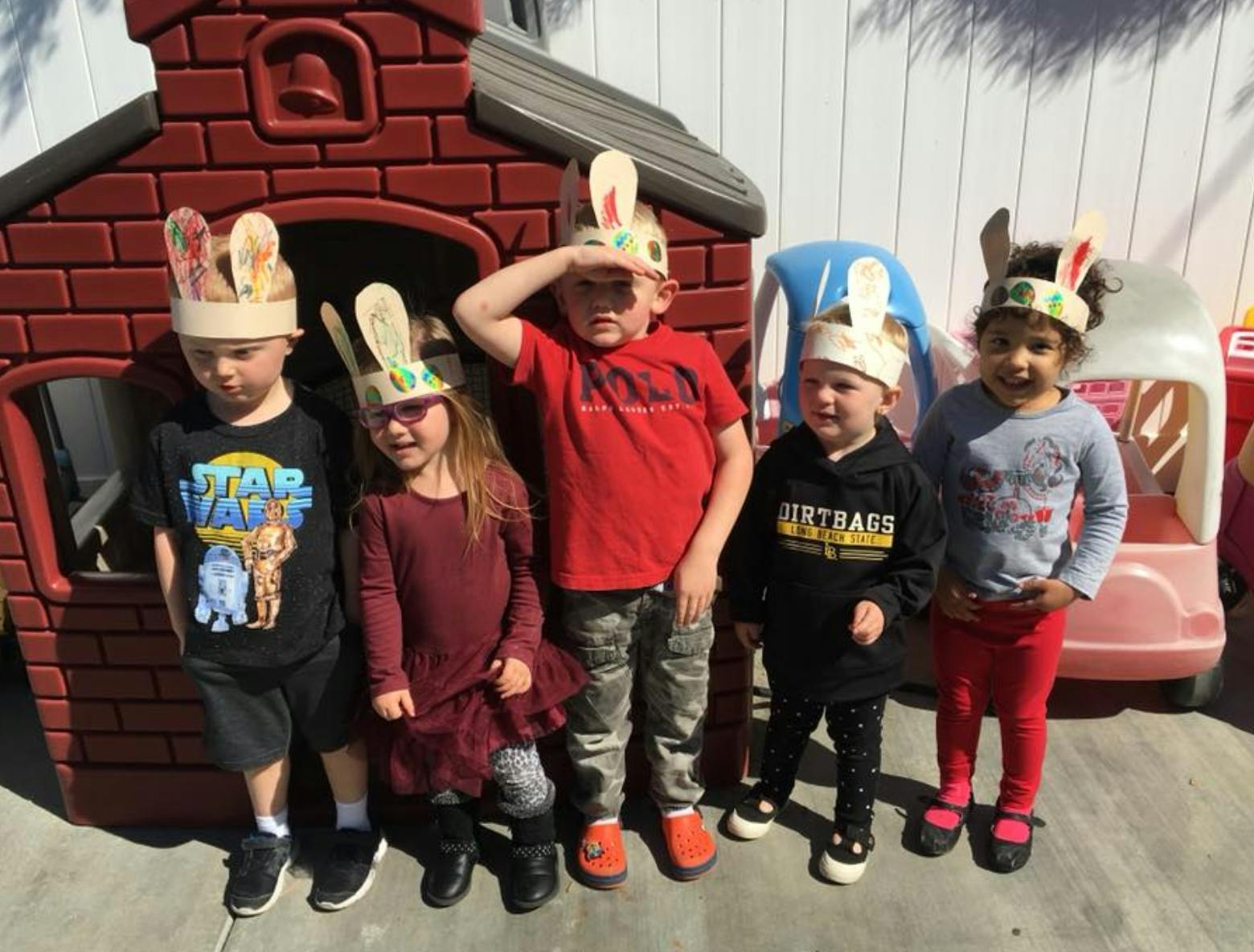 Five children wearing bunny ear headbands standing outdoors
