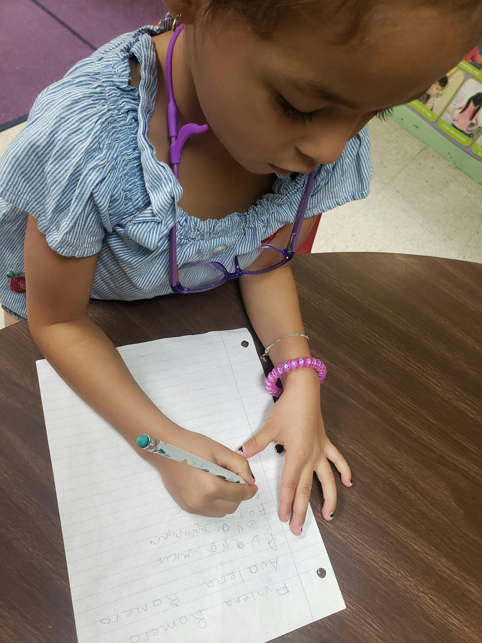 Child writing on paper at a table