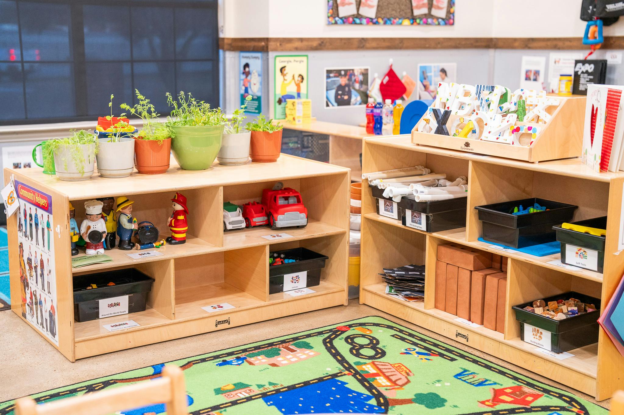 Classroom storage shelves with toy figures and building blocks on a play rug