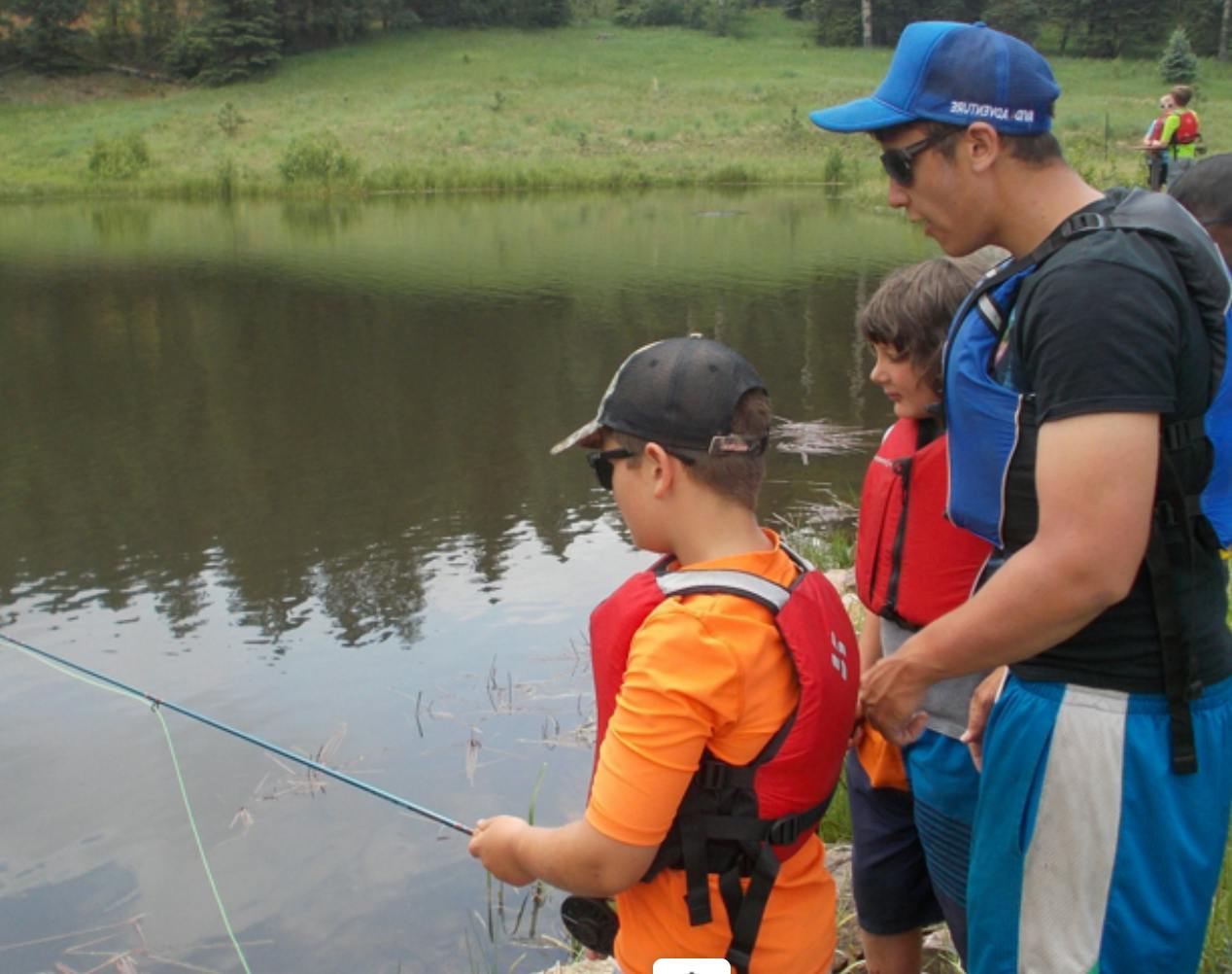 Person and two children fishing by a lake