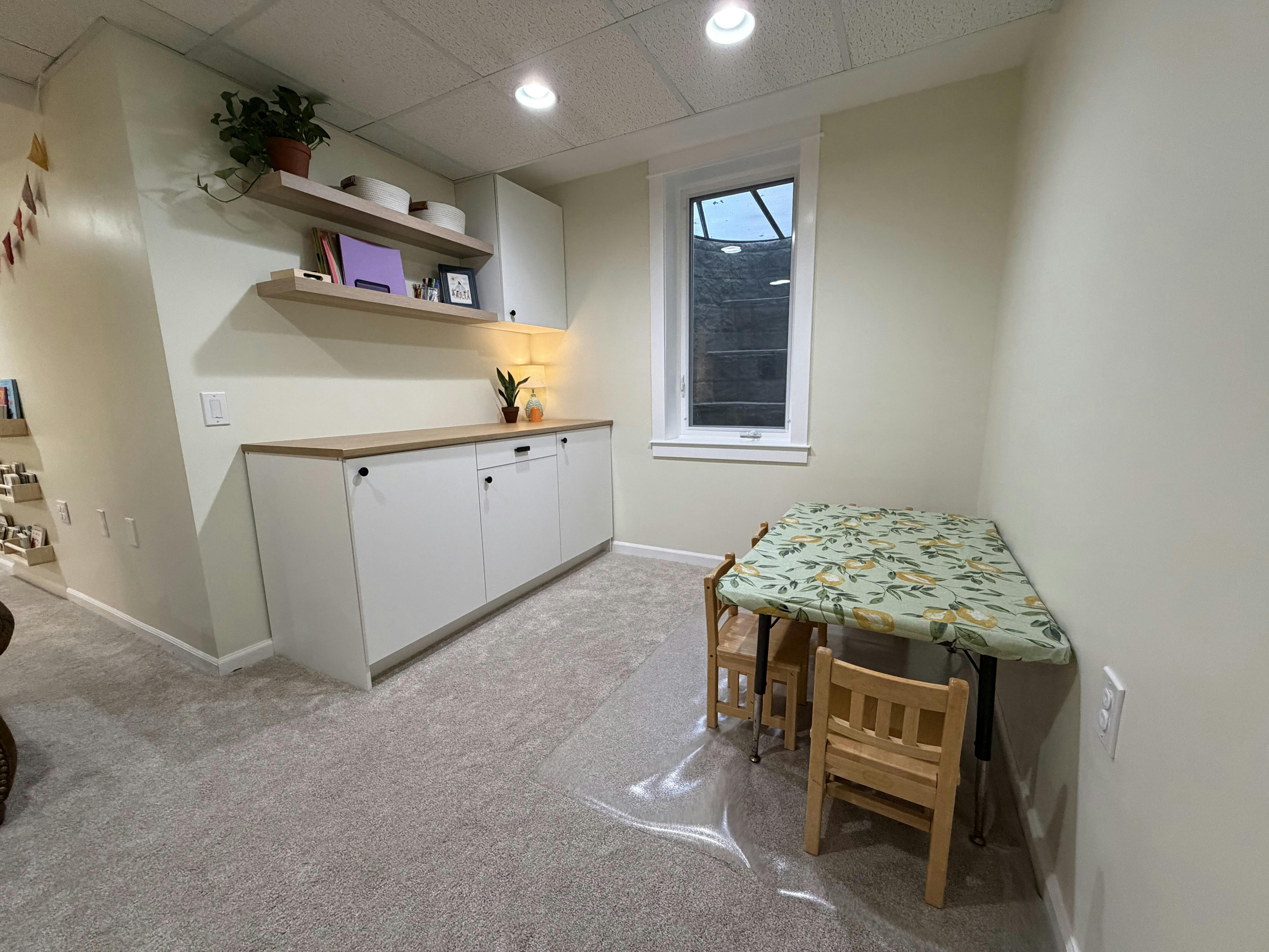 Small table and chairs with shelves in a basement playroom