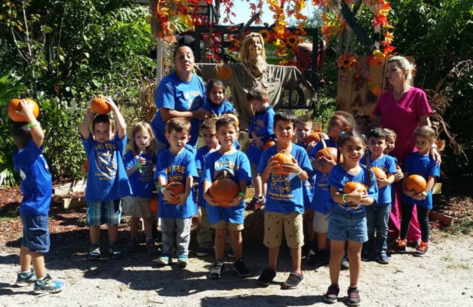 Group of children and adults holding pumpkins outdoors
