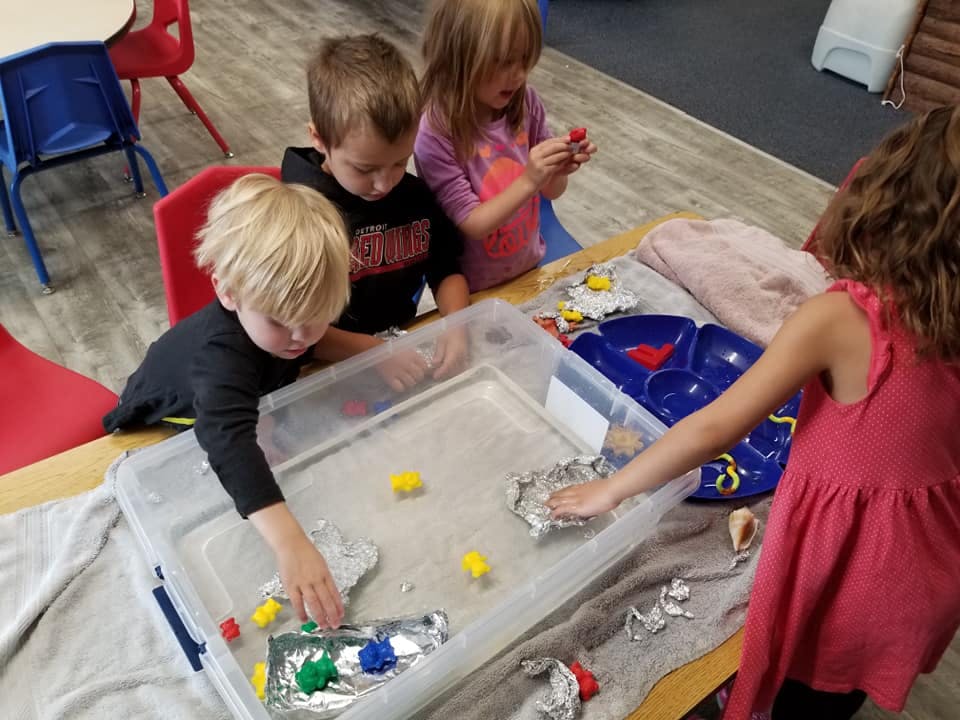 Children playing with items in a clear bin