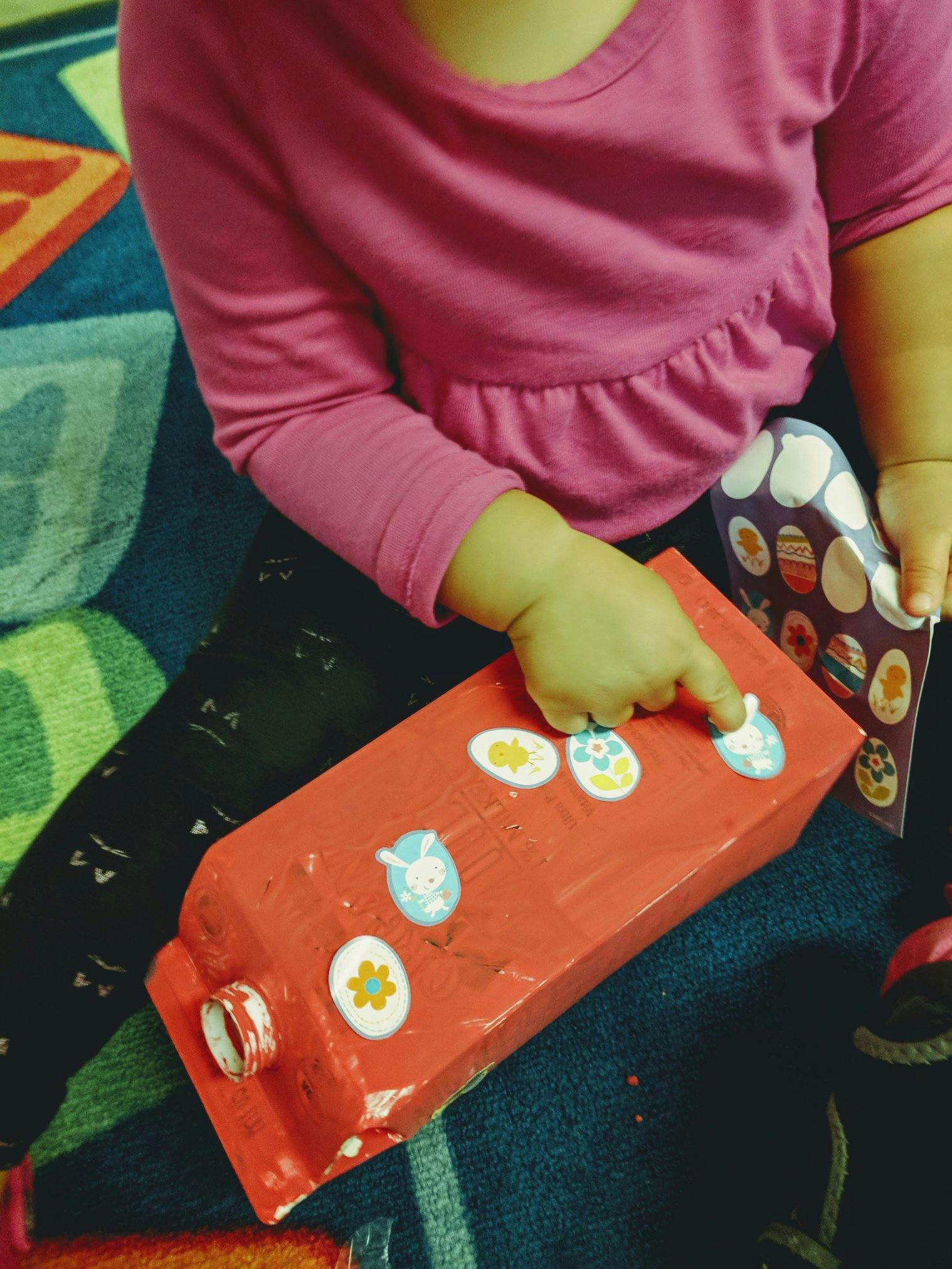 Child placing stickers on a red box