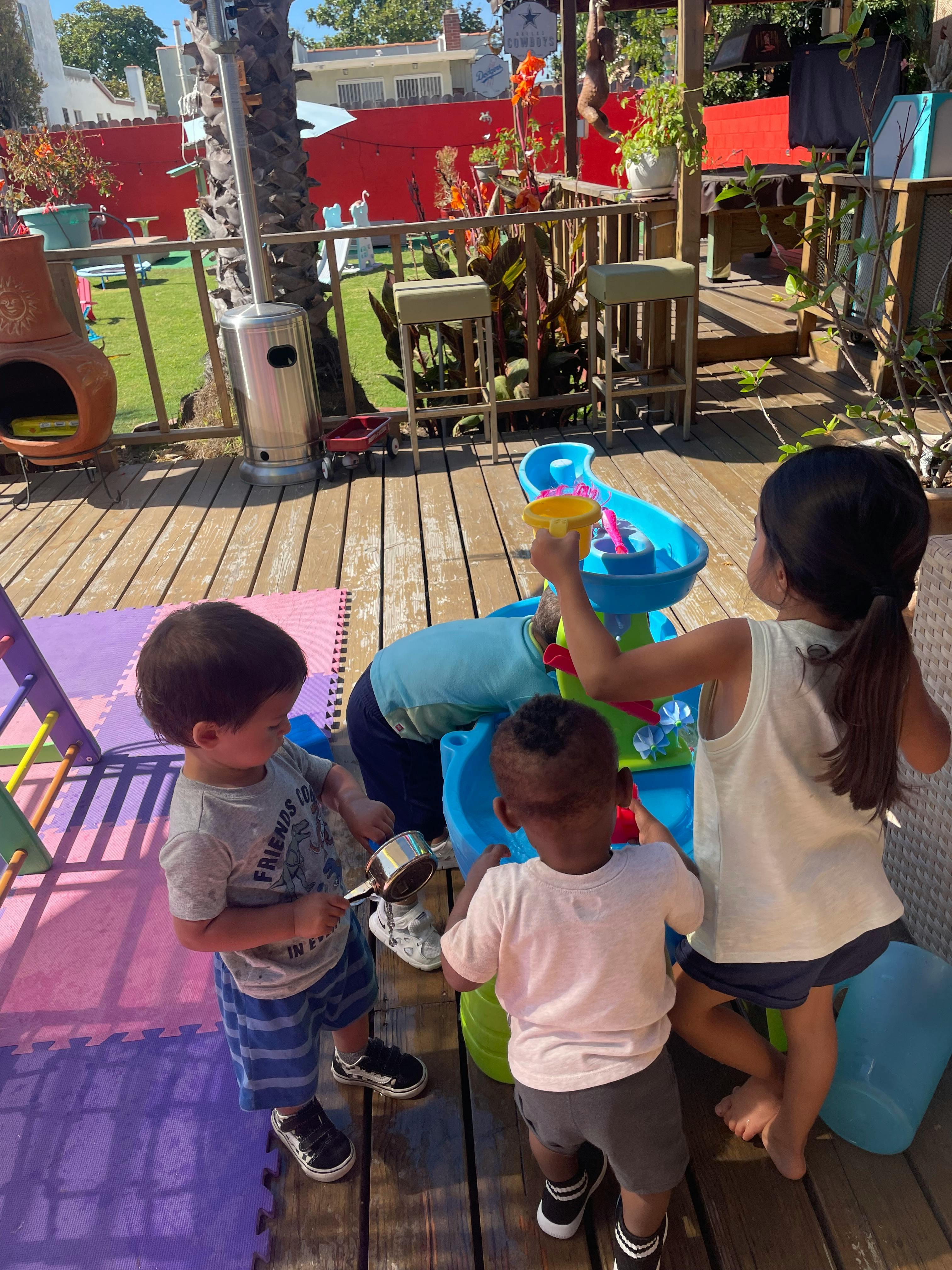 Children playing with a water table on a deck