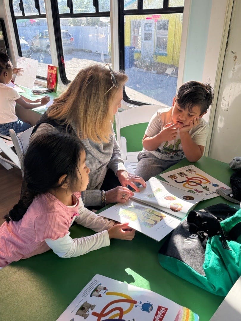 An adult and two children reading a book together at a table