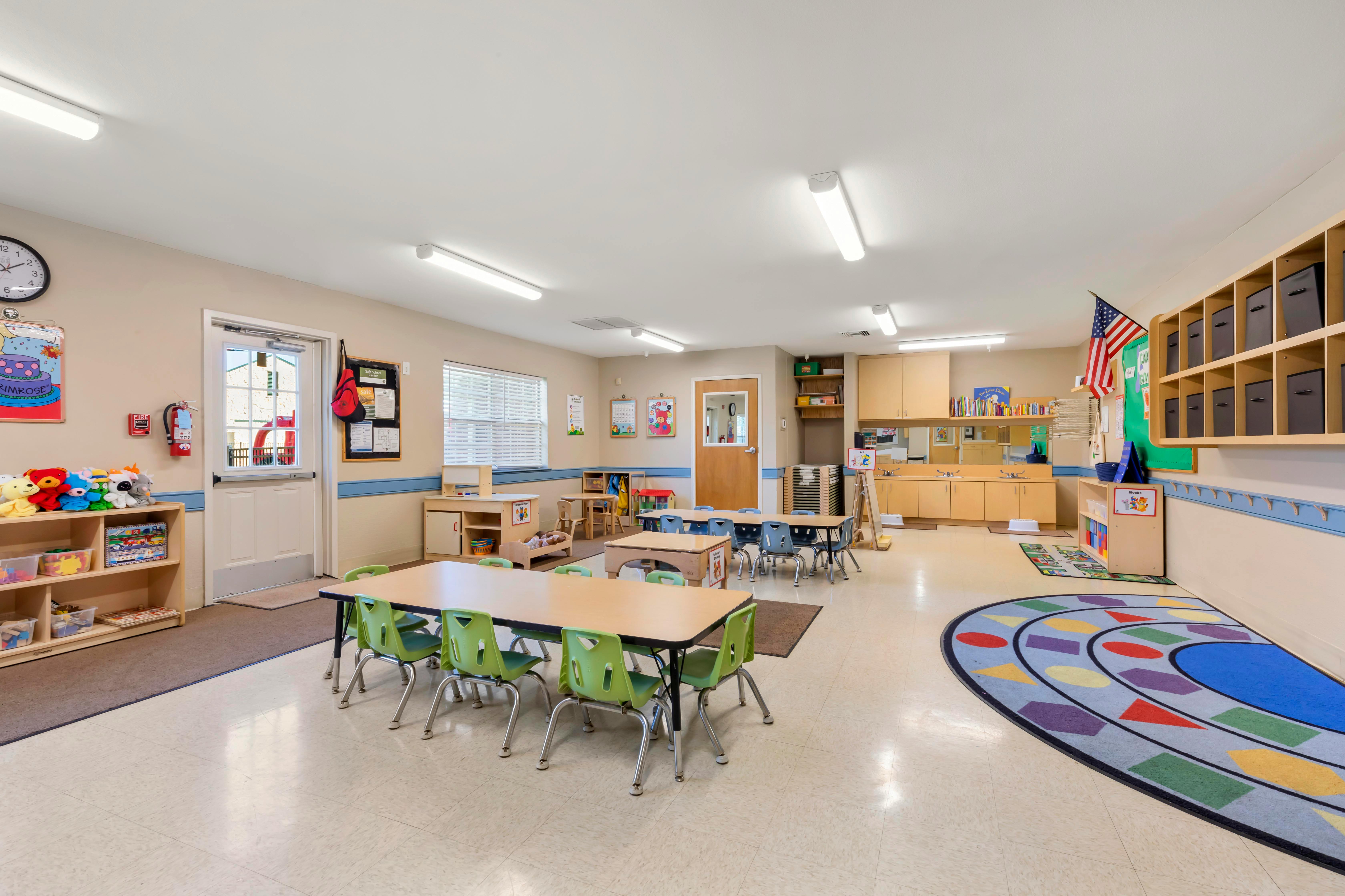 Empty preschool classroom with tables chairs and play areas