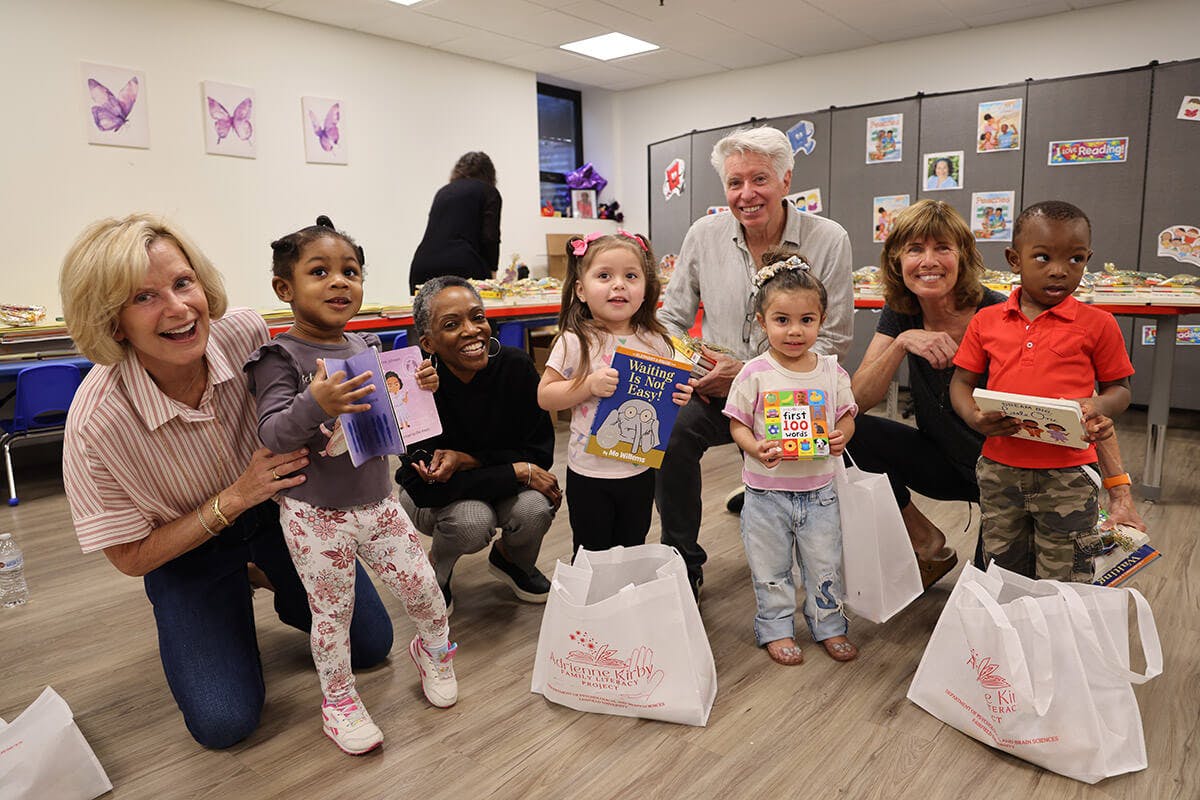 Group of adults and children holding books and smiling