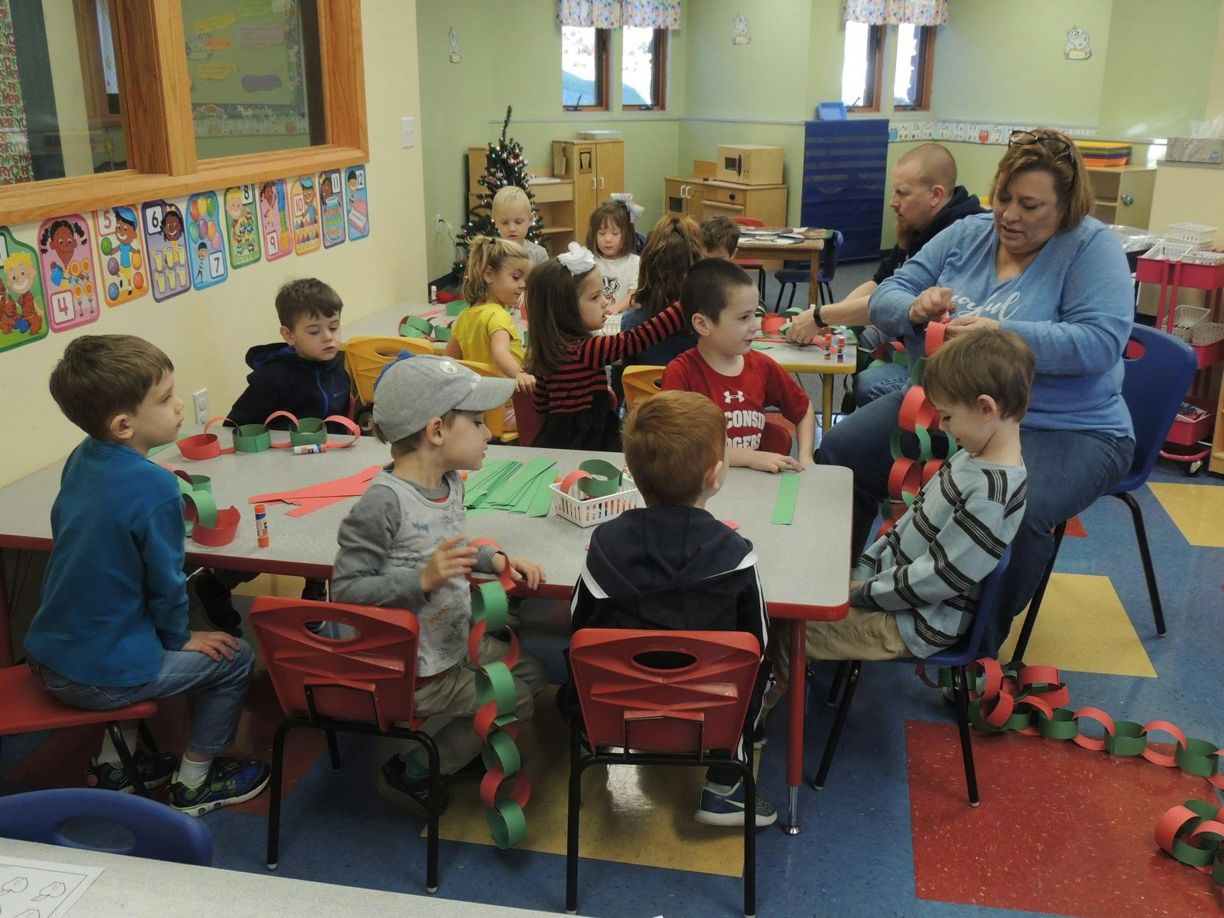 Adult and children sitting at tables in a classroom