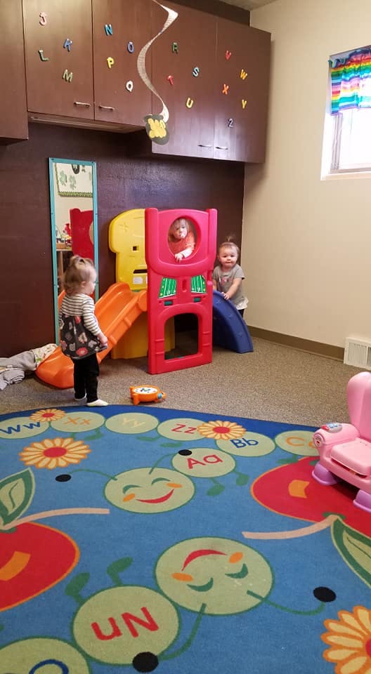 Three children playing on a colorful indoor slide and play structure