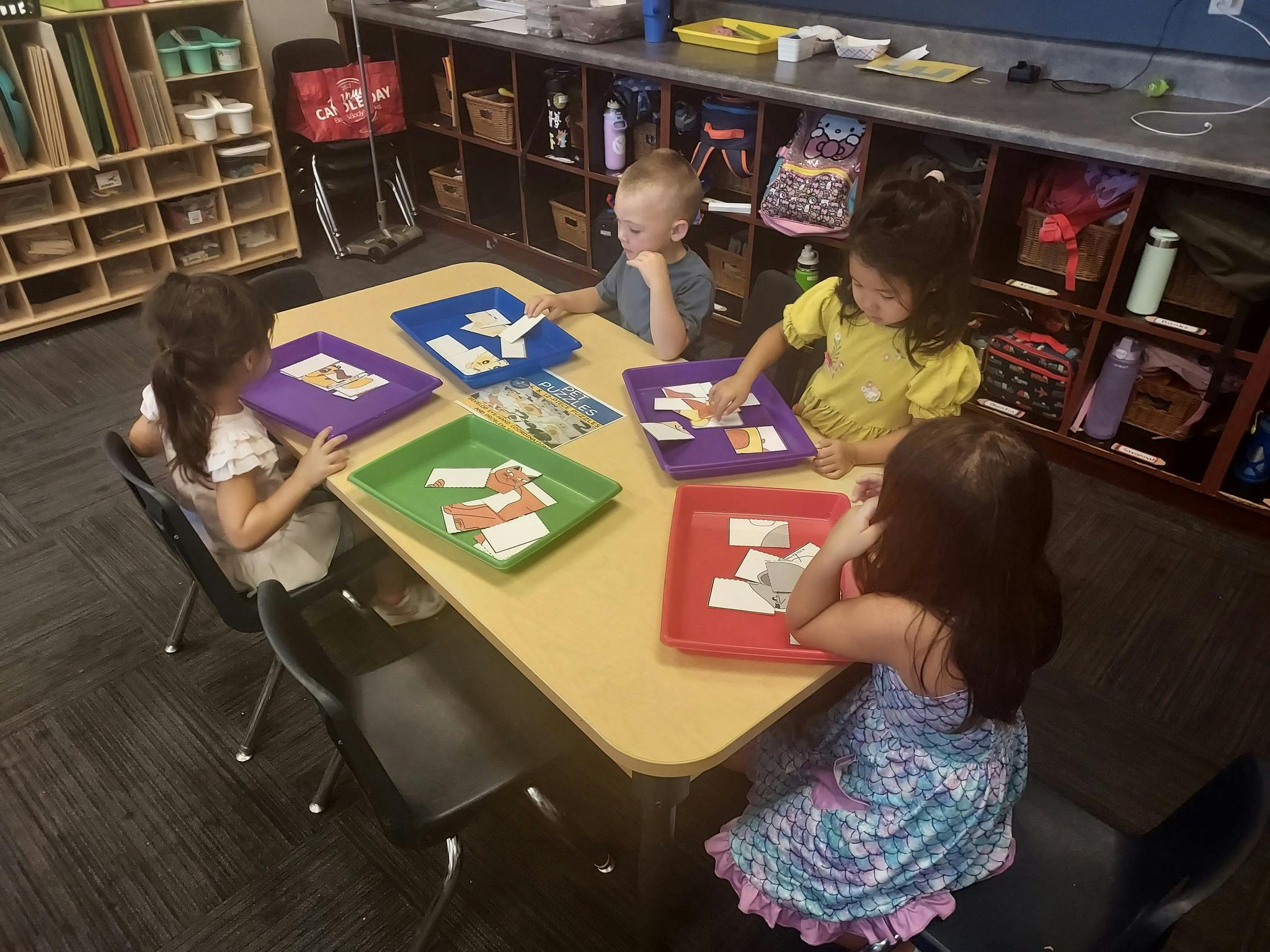 Children at a table with colorful trays and cards in a classroom