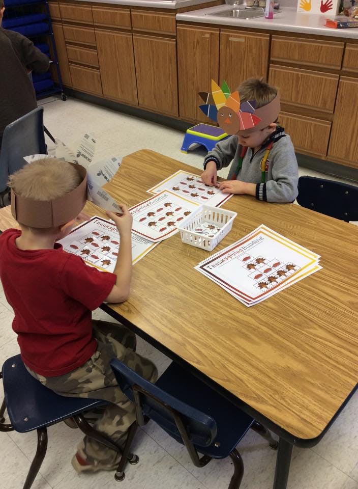 Two children at a table doing an activity with papers