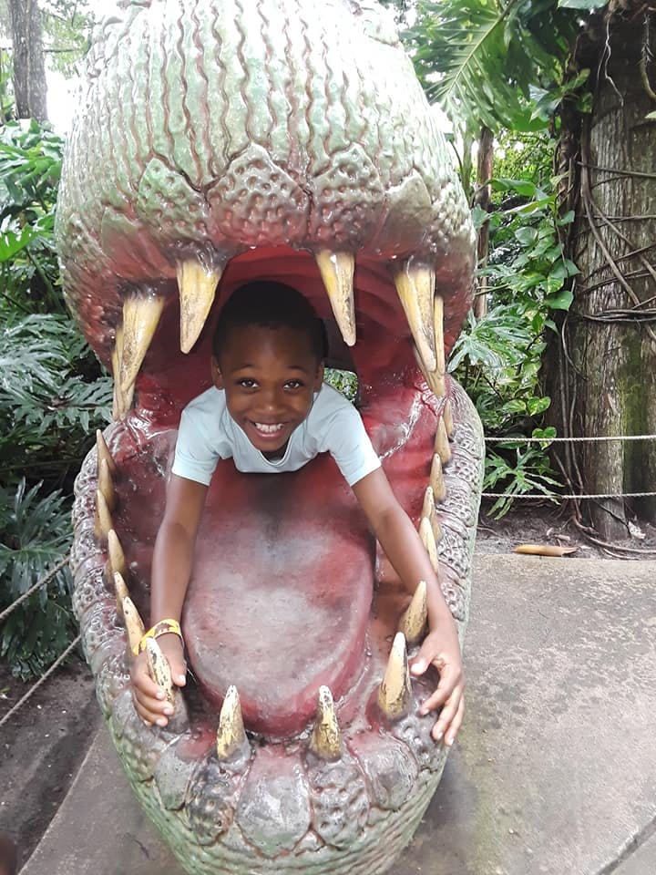 Child inside a large dinosaur head with an open mouth
