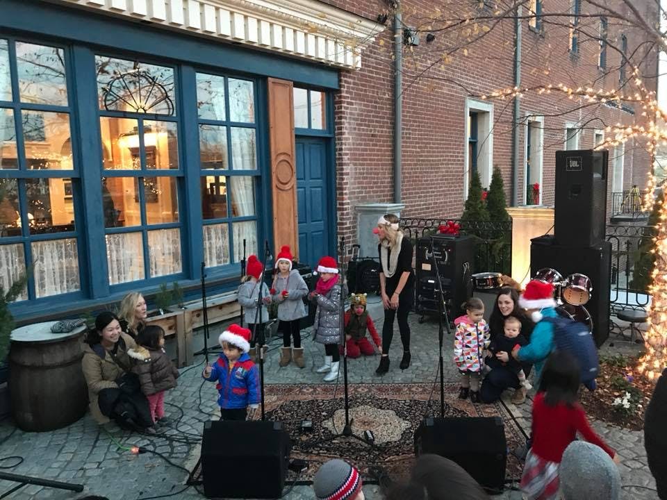 Adults and children in Santa hats singing outdoors