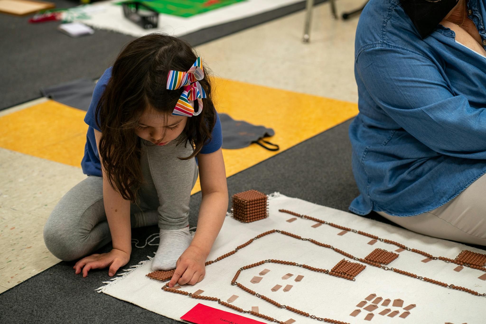 Child kneeling on floor, working with small objects on a mat