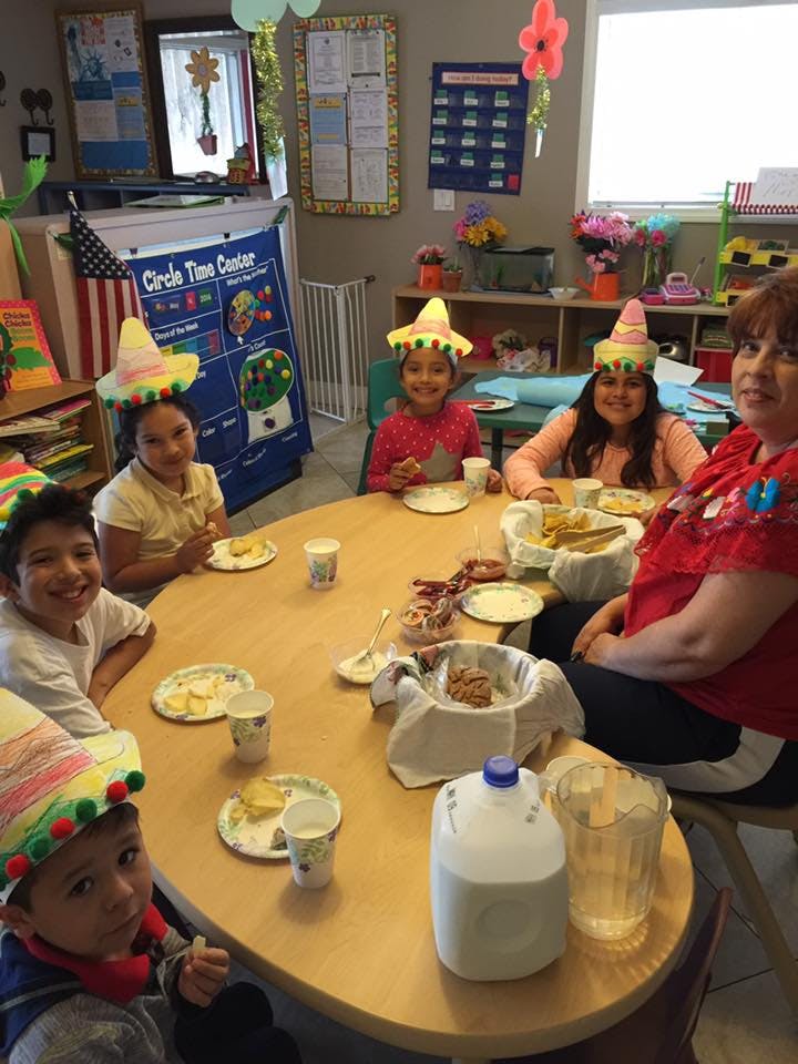 People wearing sombreros sitting around a table with food and drinks