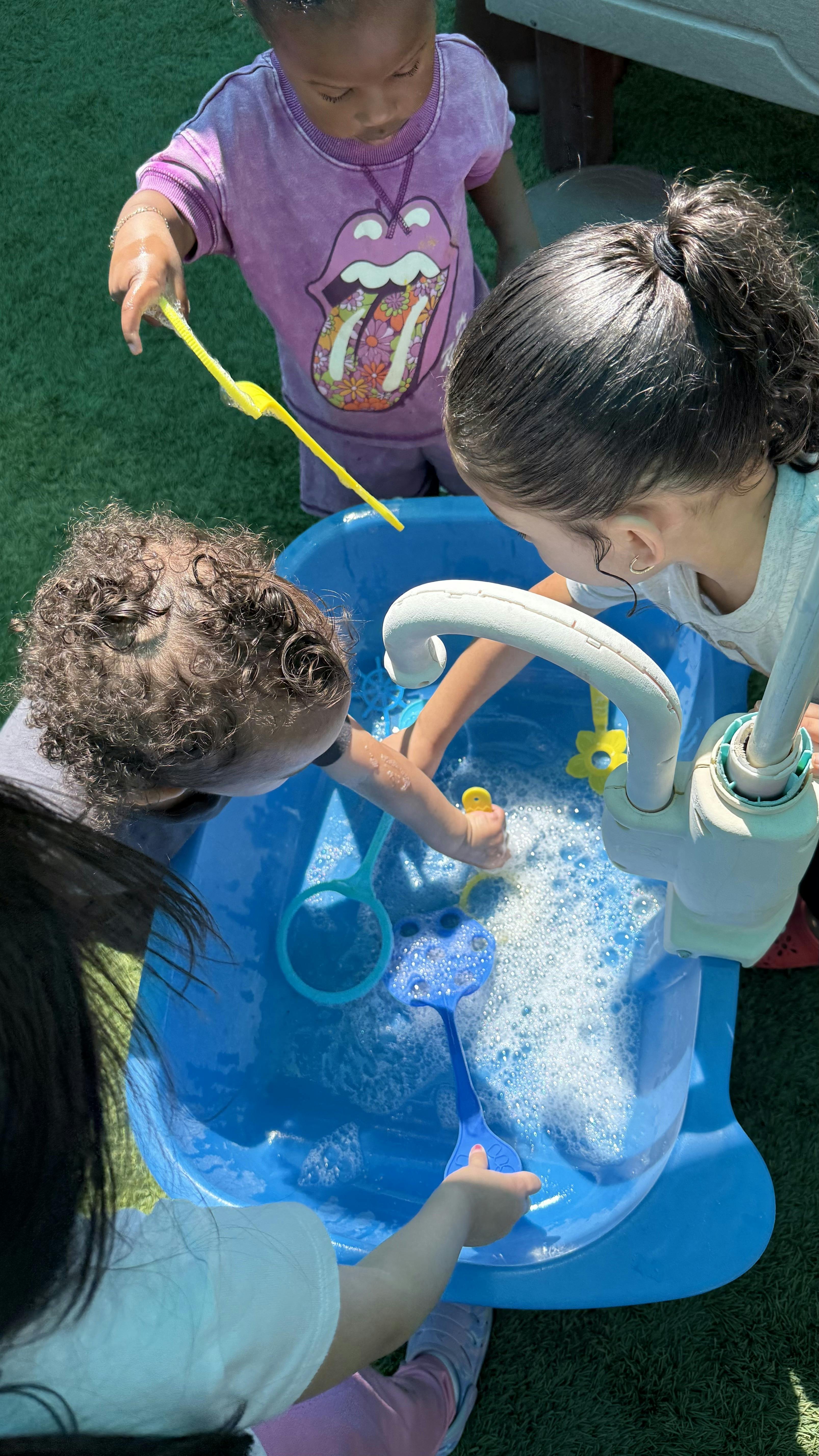 Children playing with a bubble-filled blue water table