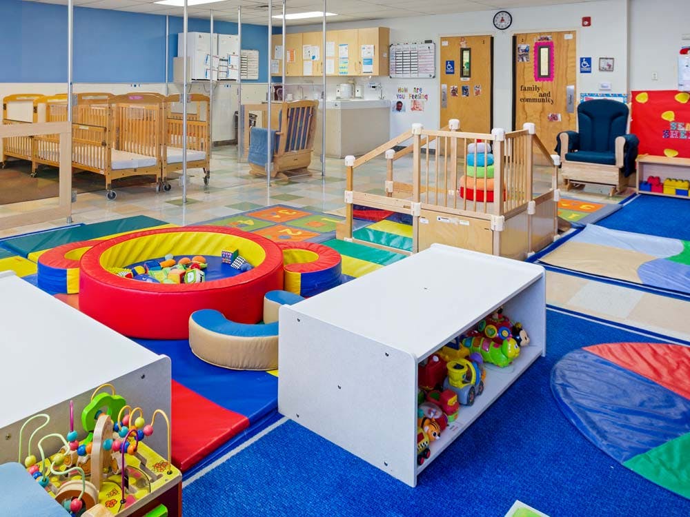 Colorful playroom with cribs, play structures, and a soft play area