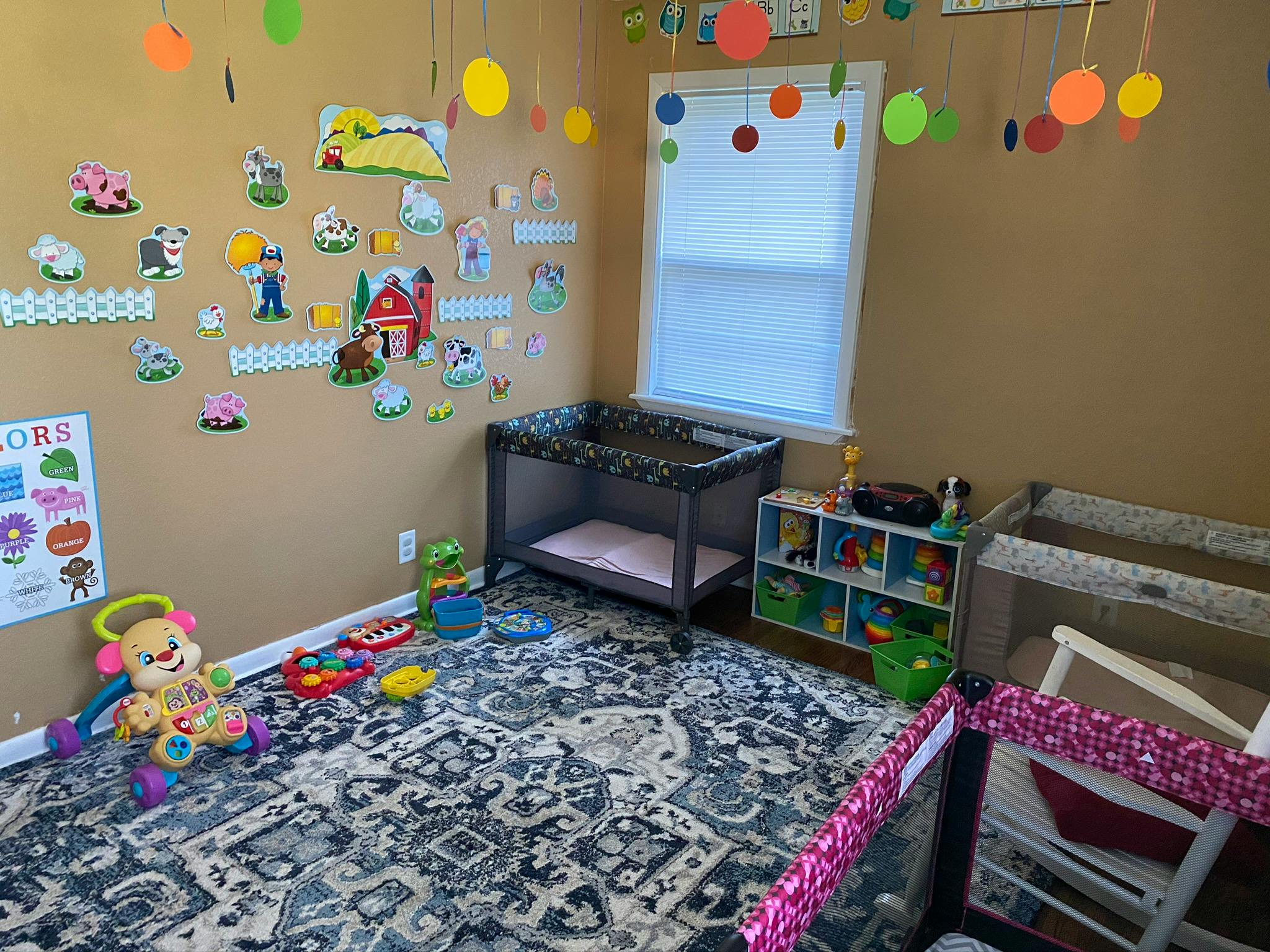 Playroom with cribs, toys, and wall decorations