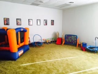 Indoor play area with bounce house, slide, and other play equipment