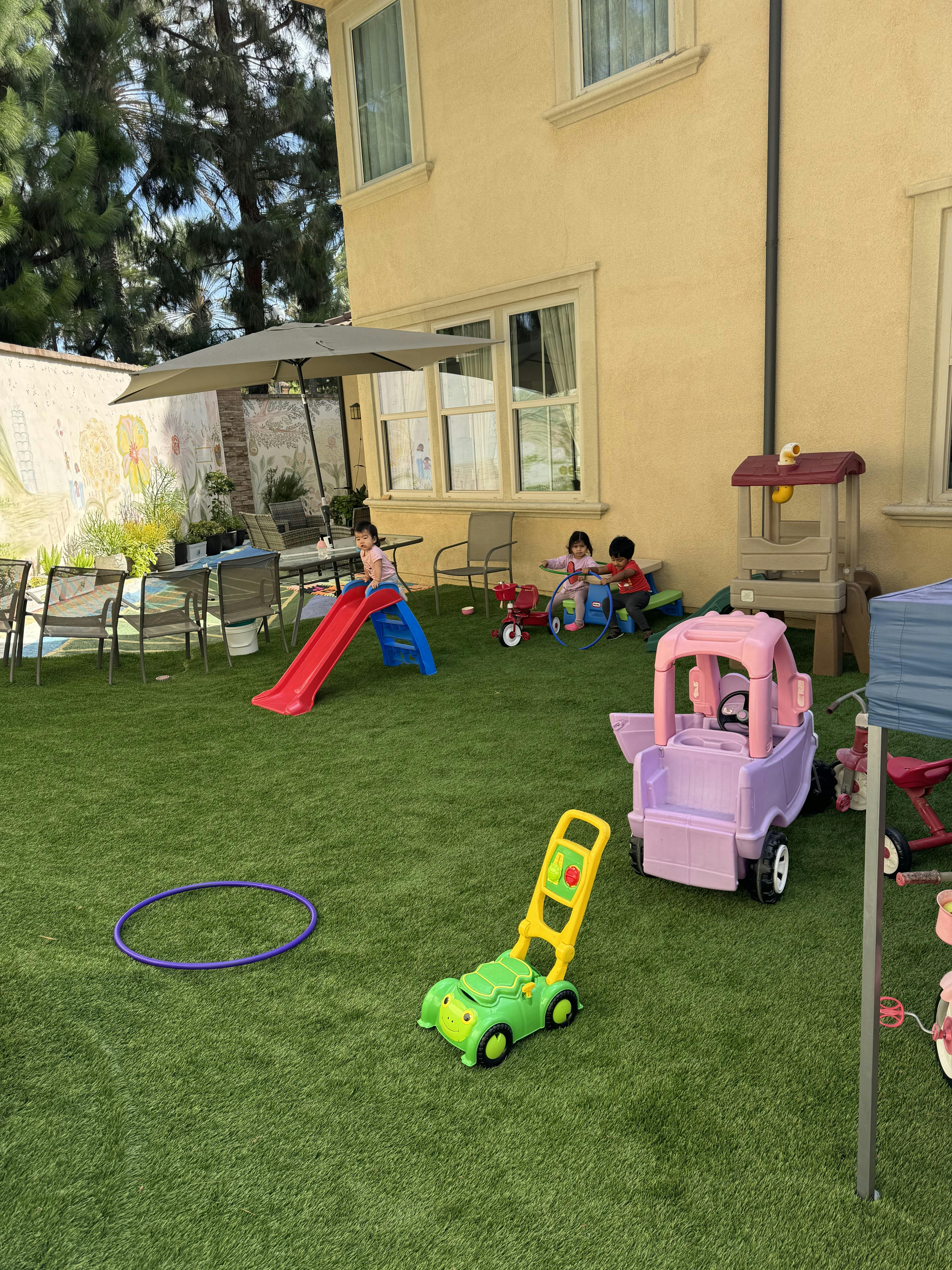 Children playing with toys in a backyard with artificial grass