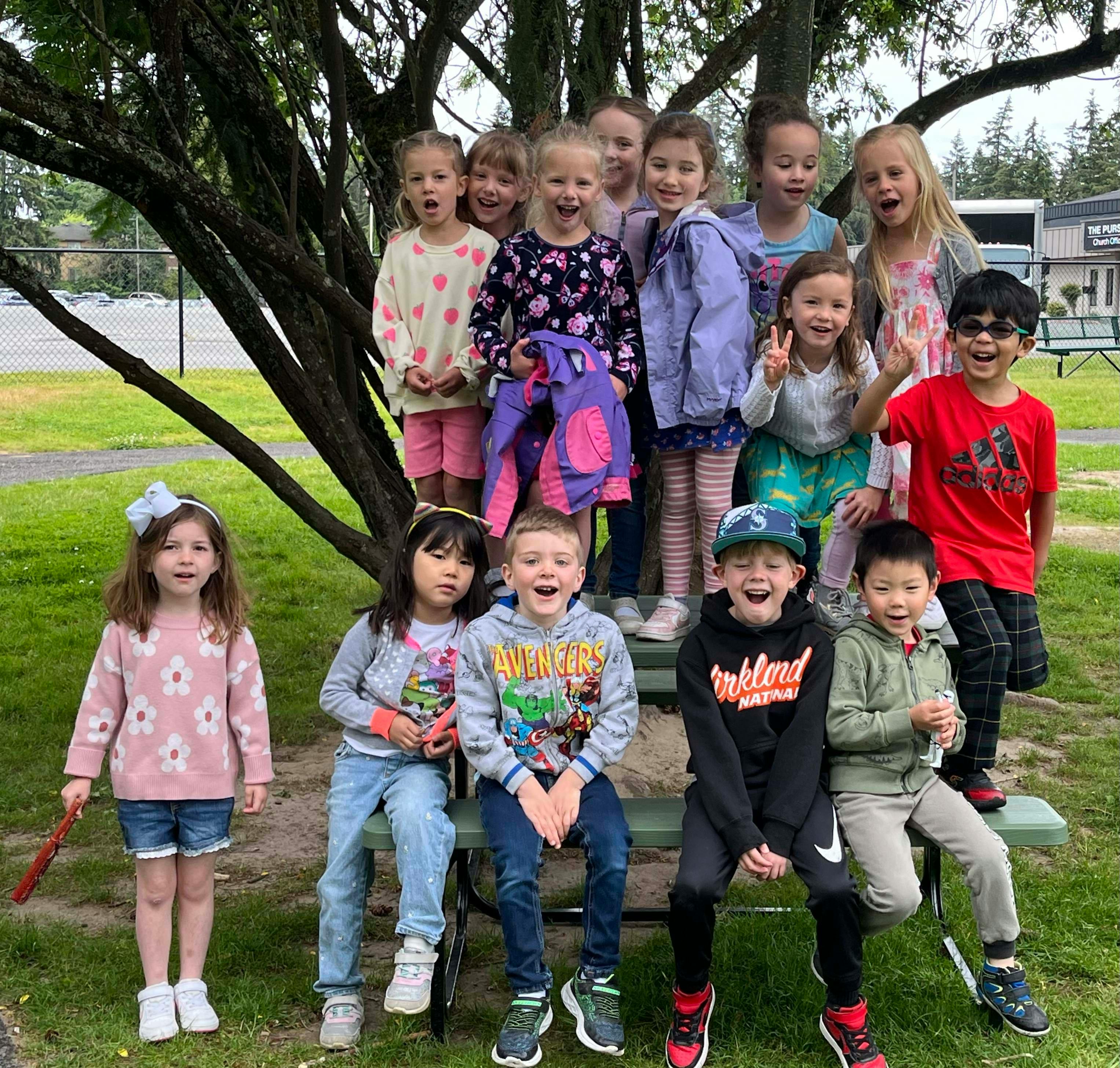 Group of children posing outdoors, some standing and some sitting on a bench