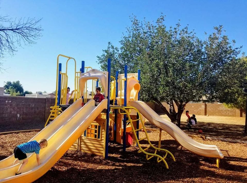 Children playing on a playground slide and climbing structure