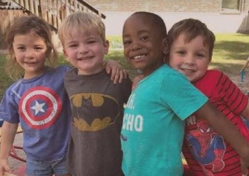 Four children standing together, smiling