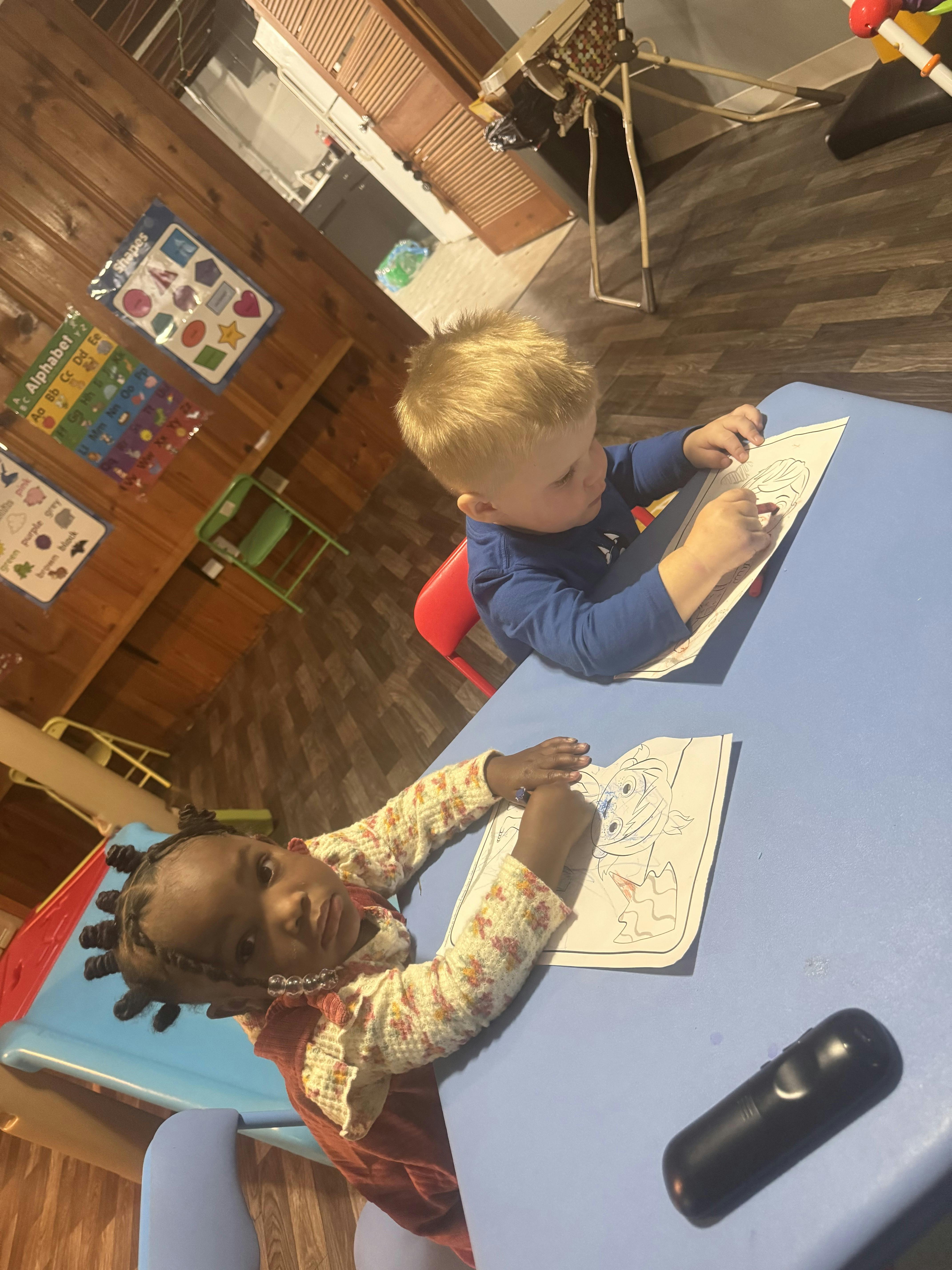 Two children drawing at a table