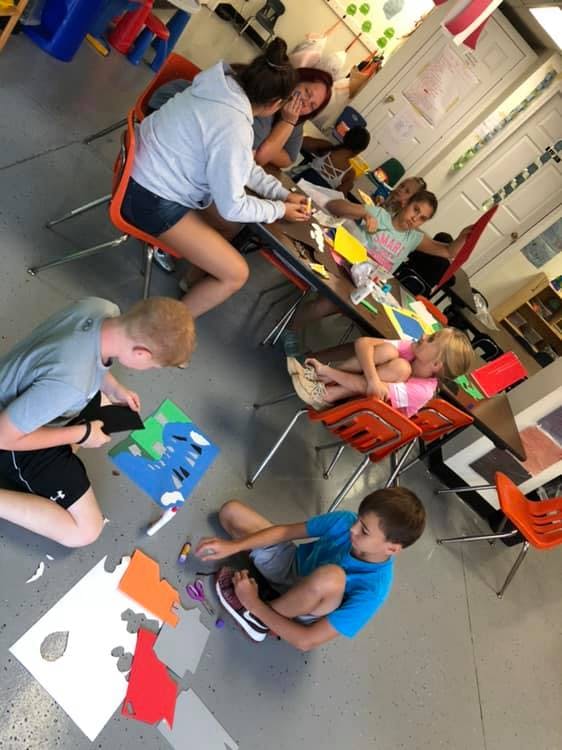 People and children working on crafts in a classroom