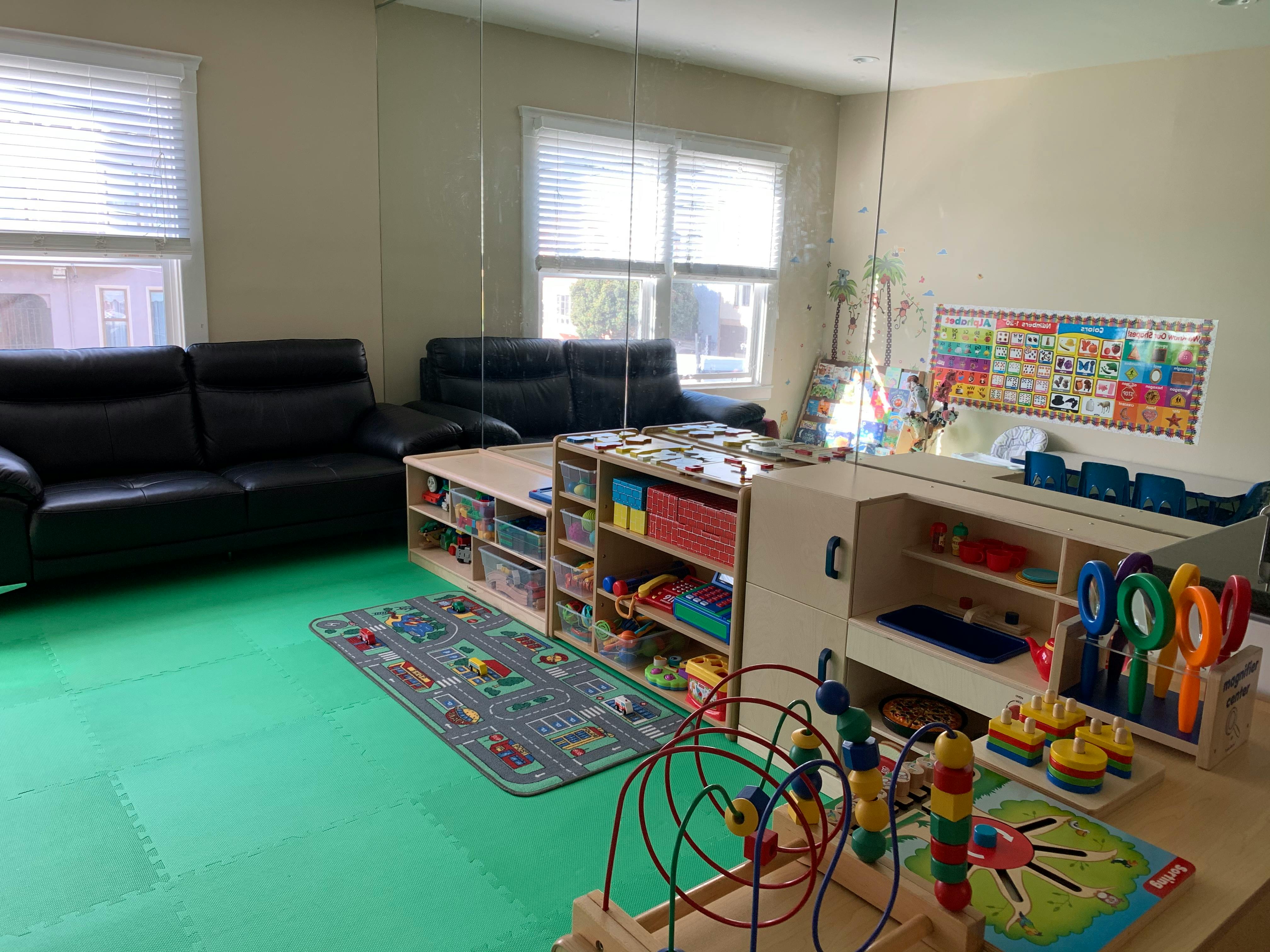 Playroom with toys, shelves, and black couches
