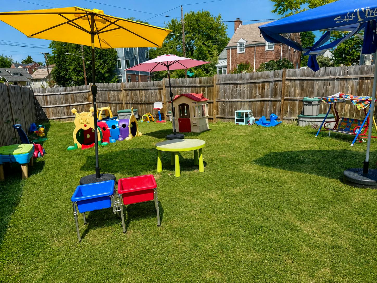 Backyard play area with various children's play equipment and umbrellas
