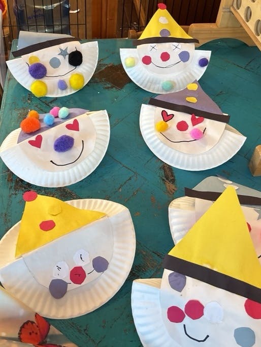 Paper plate clown faces with party hats and pom-pom noses