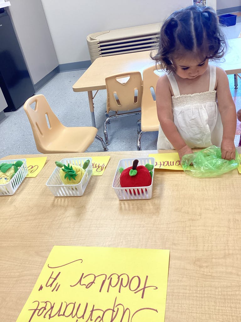 Child playing with toy fruit on a table