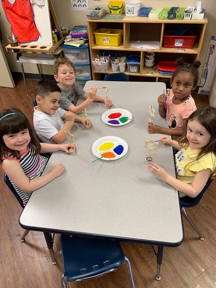 Children painting at a table in a classroom