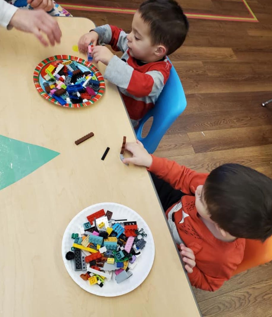 Two children playing with building blocks at a table