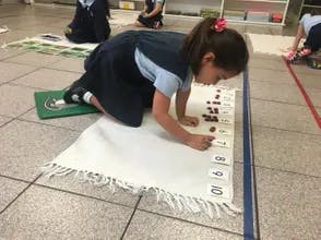 Child kneeling on floor working with number cards