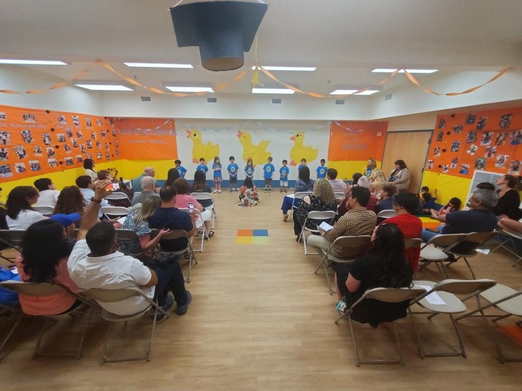 Audience seated in rows facing a group of people standing on a stage