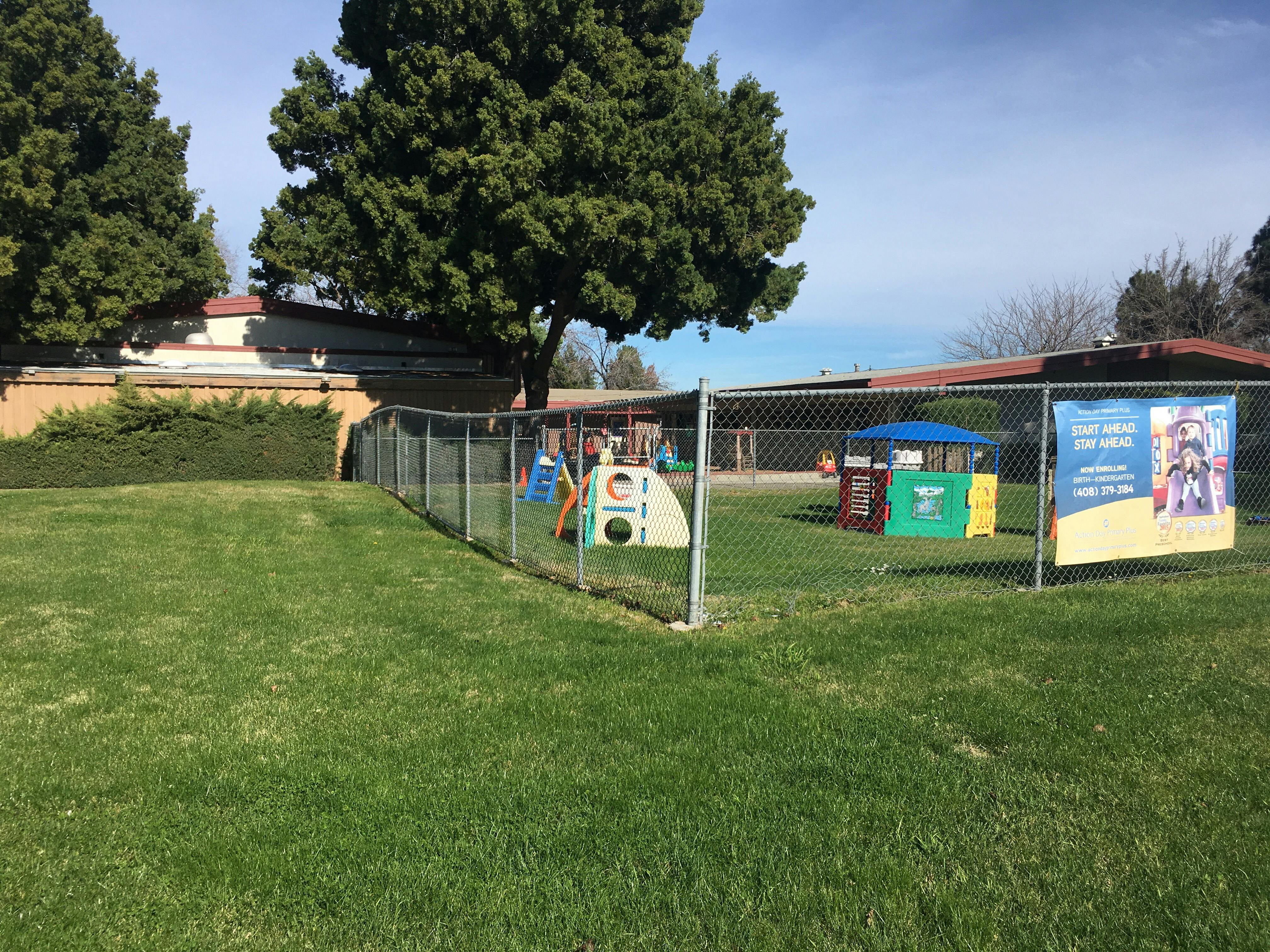 Playground with a slide and other play equipment behind a chain link fence