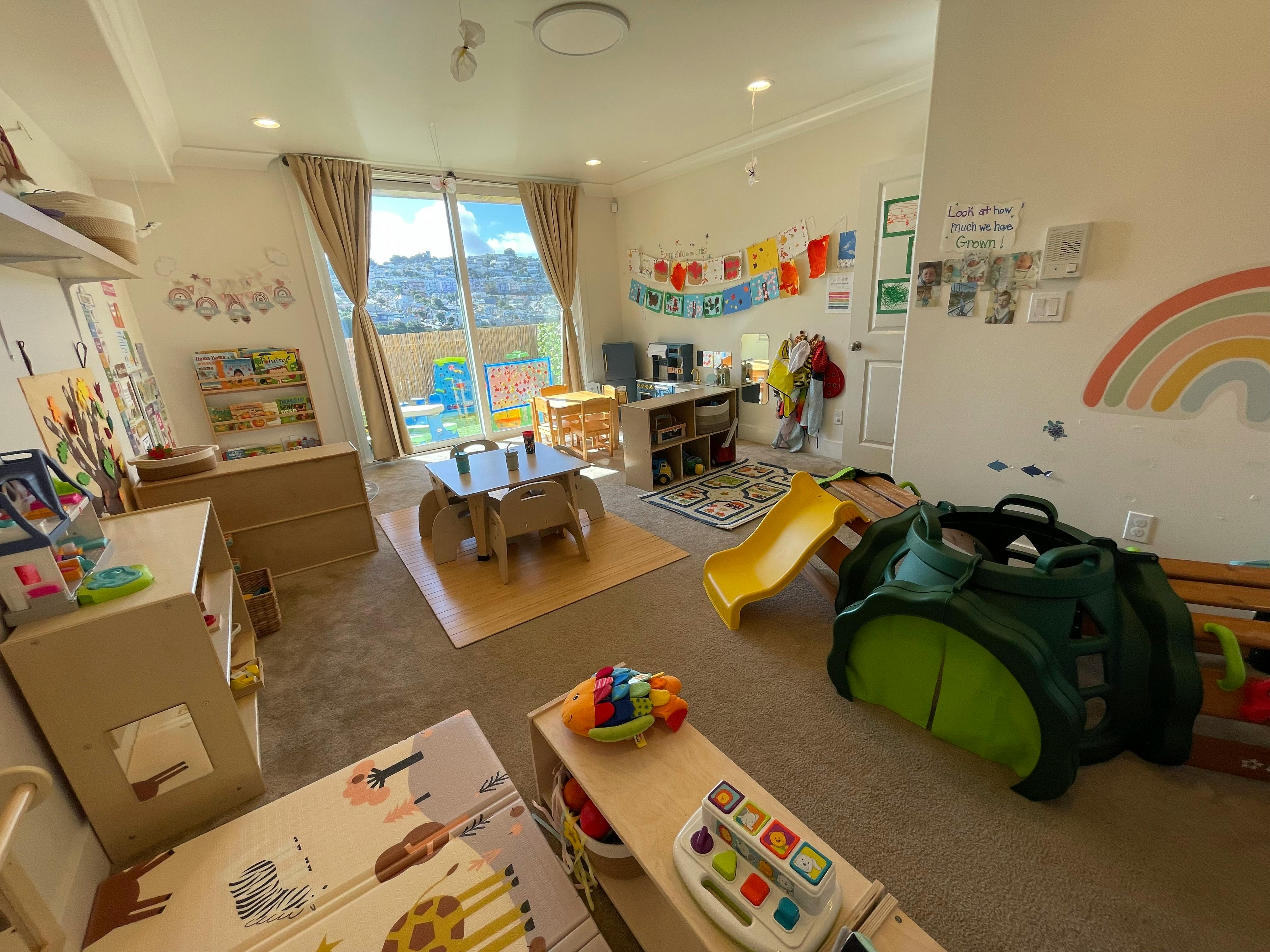 Playroom with small tables, chairs, a yellow slide, and toys