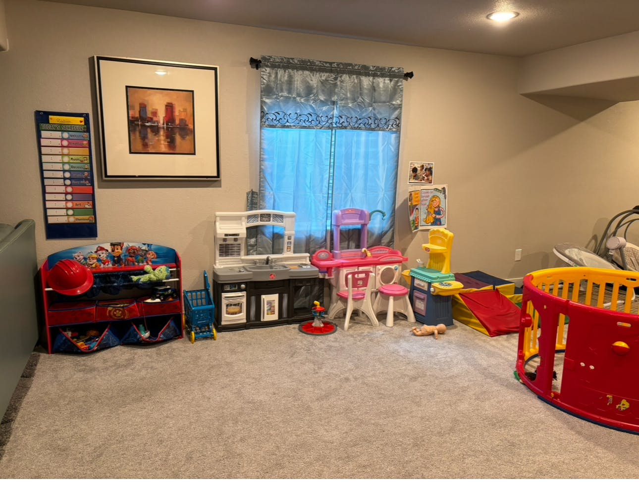 Playroom with various toys, including a play kitchen, table, and playpen