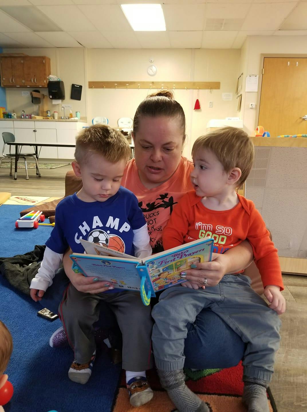 Person reading a book to two children