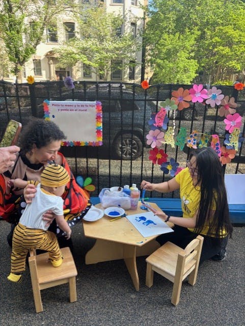 Two people and a child painting at a small table outdoors