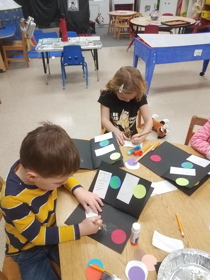 Two children working on craft projects at a table