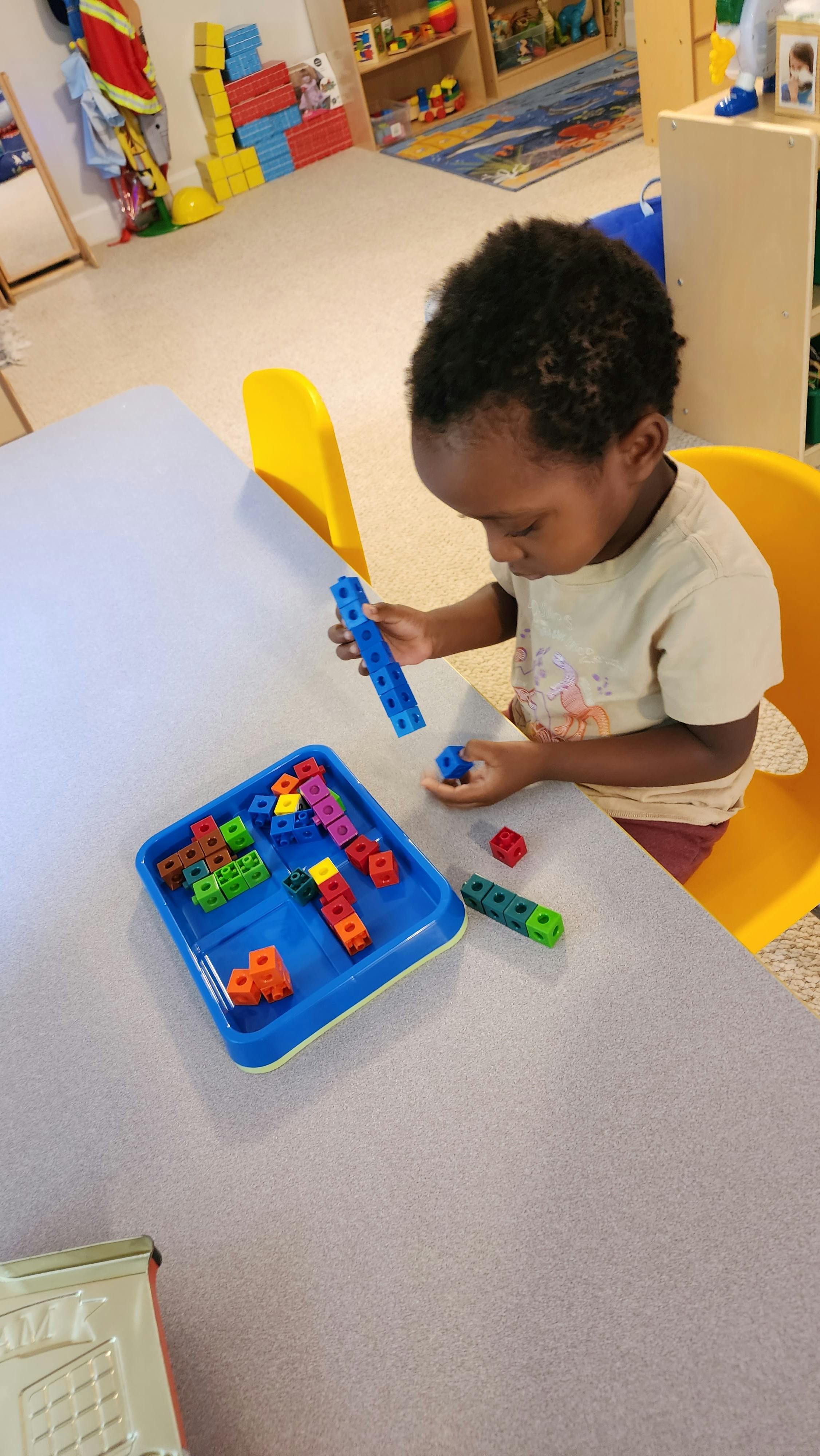 Child playing with colorful interlocking blocks at a table