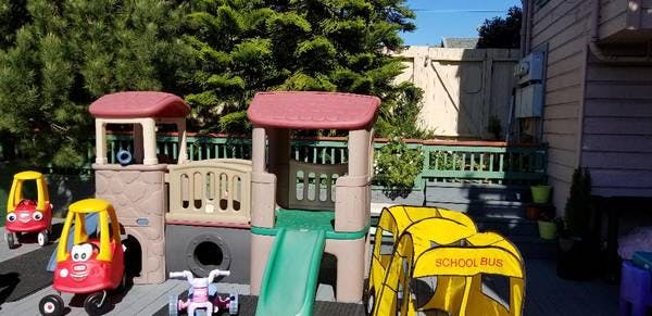 Outdoor playground with slide, playhouses, and ride-on toys